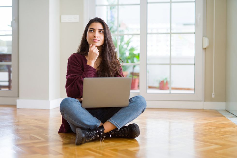 Una mujer en una computadora portátil piensa en sus fortalezas personales mientras intenta cambiar de carrera