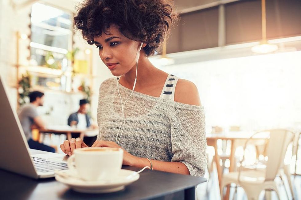 Woman on laptop writes her resume in a cafe