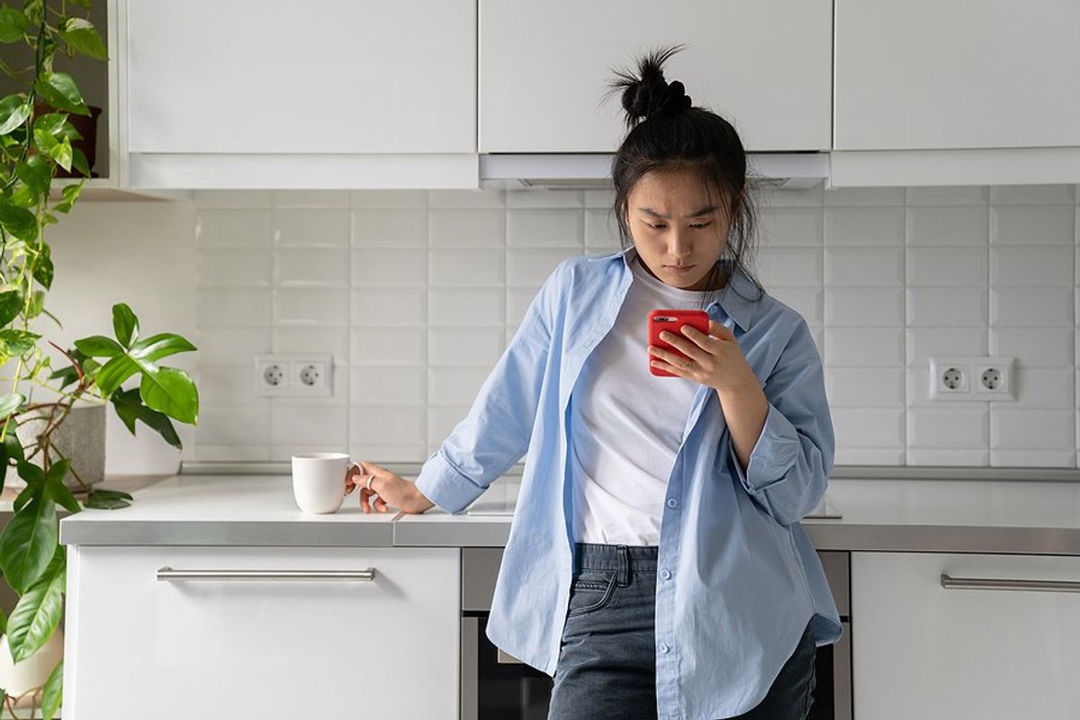 Woman on phone looks at job postings on job boards while unemployed