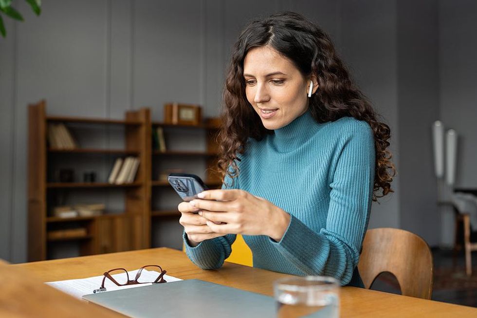 Woman on phone posts content on LinkedIn