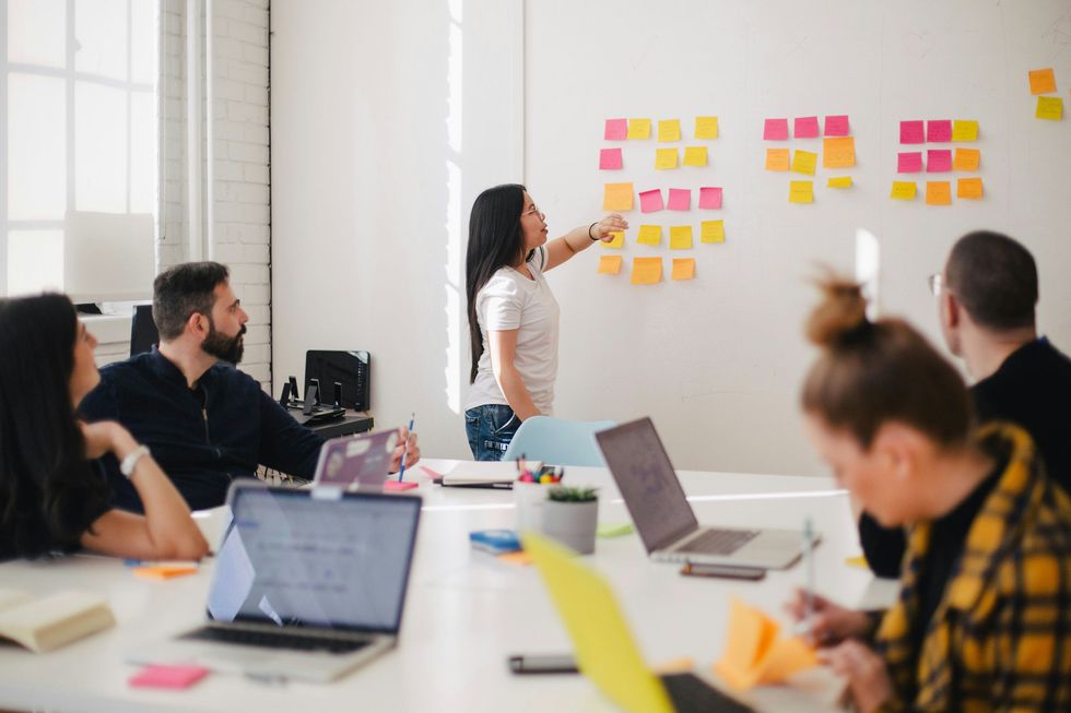 Woman placing sticky notes on wall during a project management meeting
