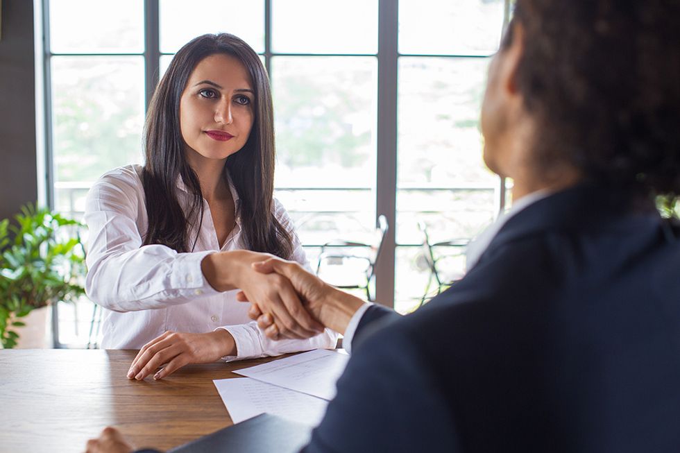 Woman quits her job the right way and shakes hands with her boss before she leaves