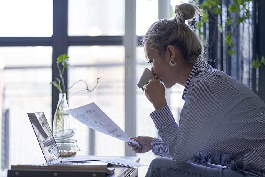 Woman reads her resume while drinking coffee