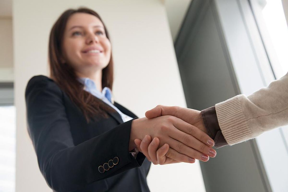 Woman shakes hands with a hiring manager after the company improves its talent acquisition strategy 