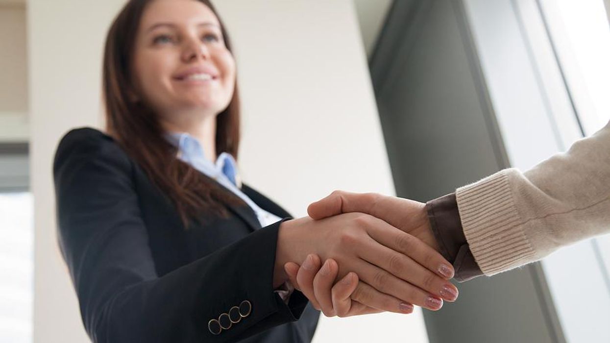 Woman shakes hands with a hiring manager after the company improves its talent acquisition strategy