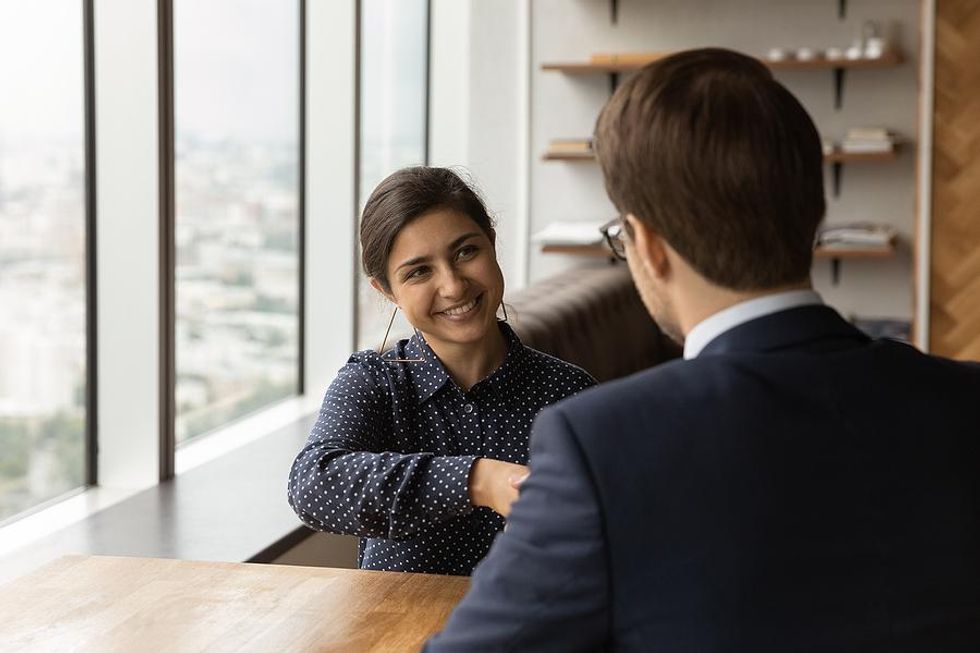 Woman shakes hands with her boss after her performance review