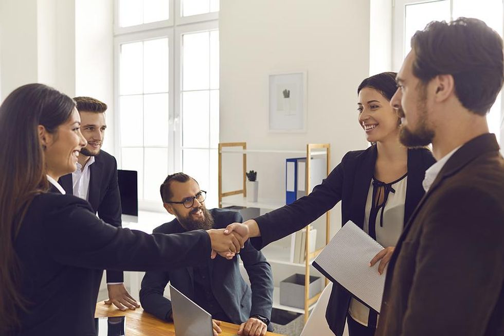 Woman shakes hands with other professionals