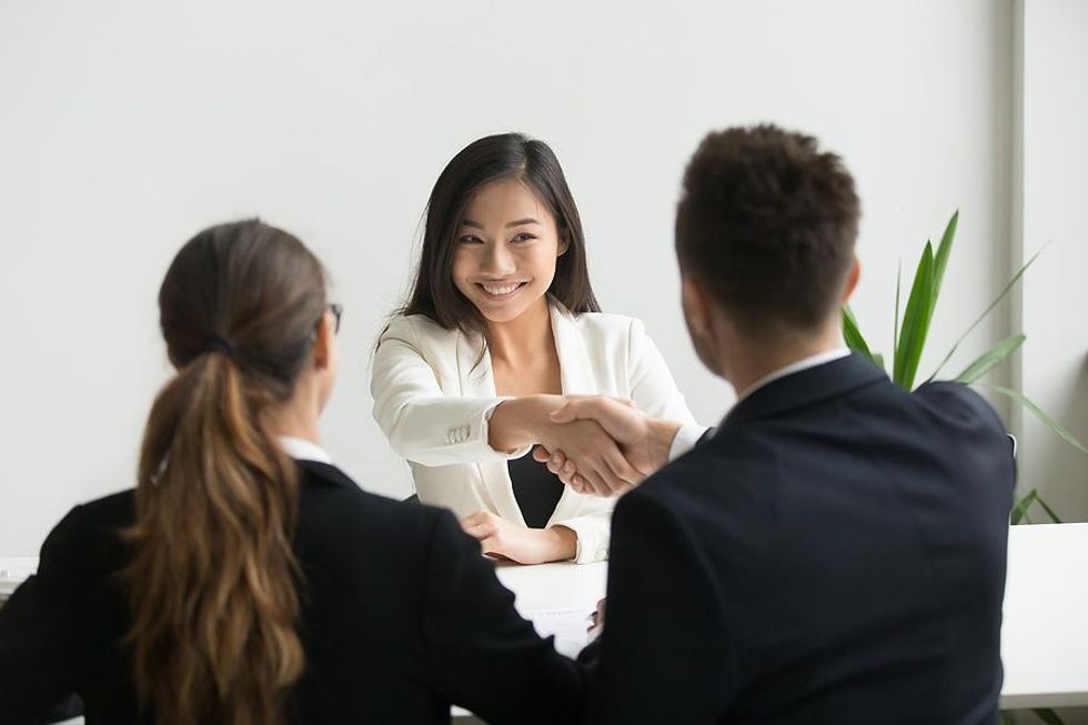 A woman shakes the hand of a hiring manager during a job interview