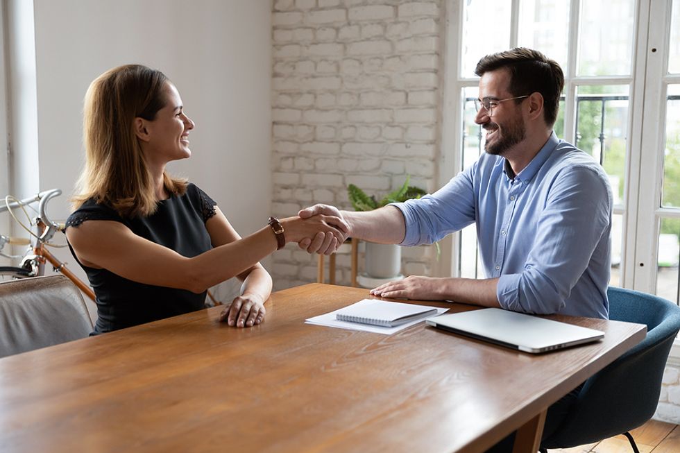 Woman shakes the hand of the hiring manager before her in-person interview