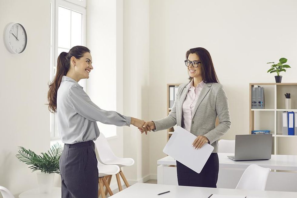 Una mujer le da la mano al gerente de contratación antes de su entrevista de trabajo