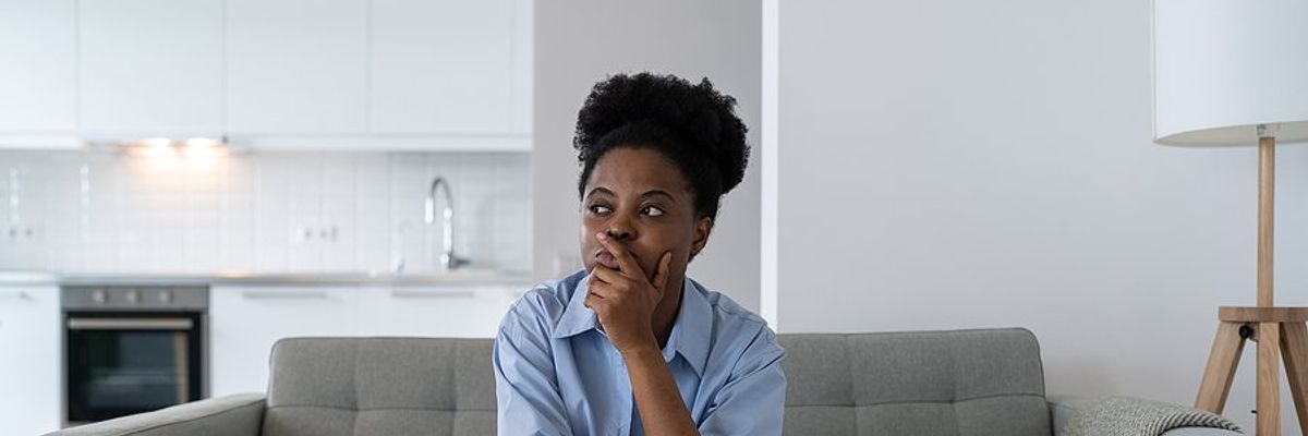 Woman sitting on couch thinks about and fears getting laid off