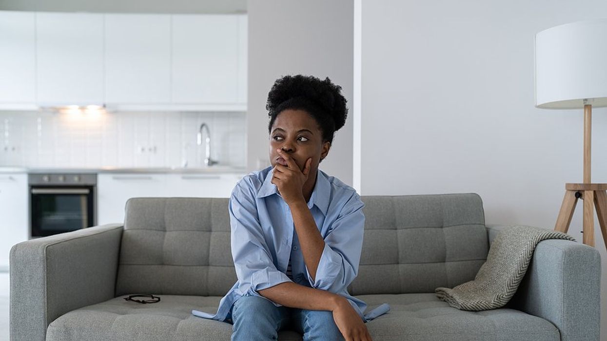 Woman sitting on couch thinks about and fears getting laid off