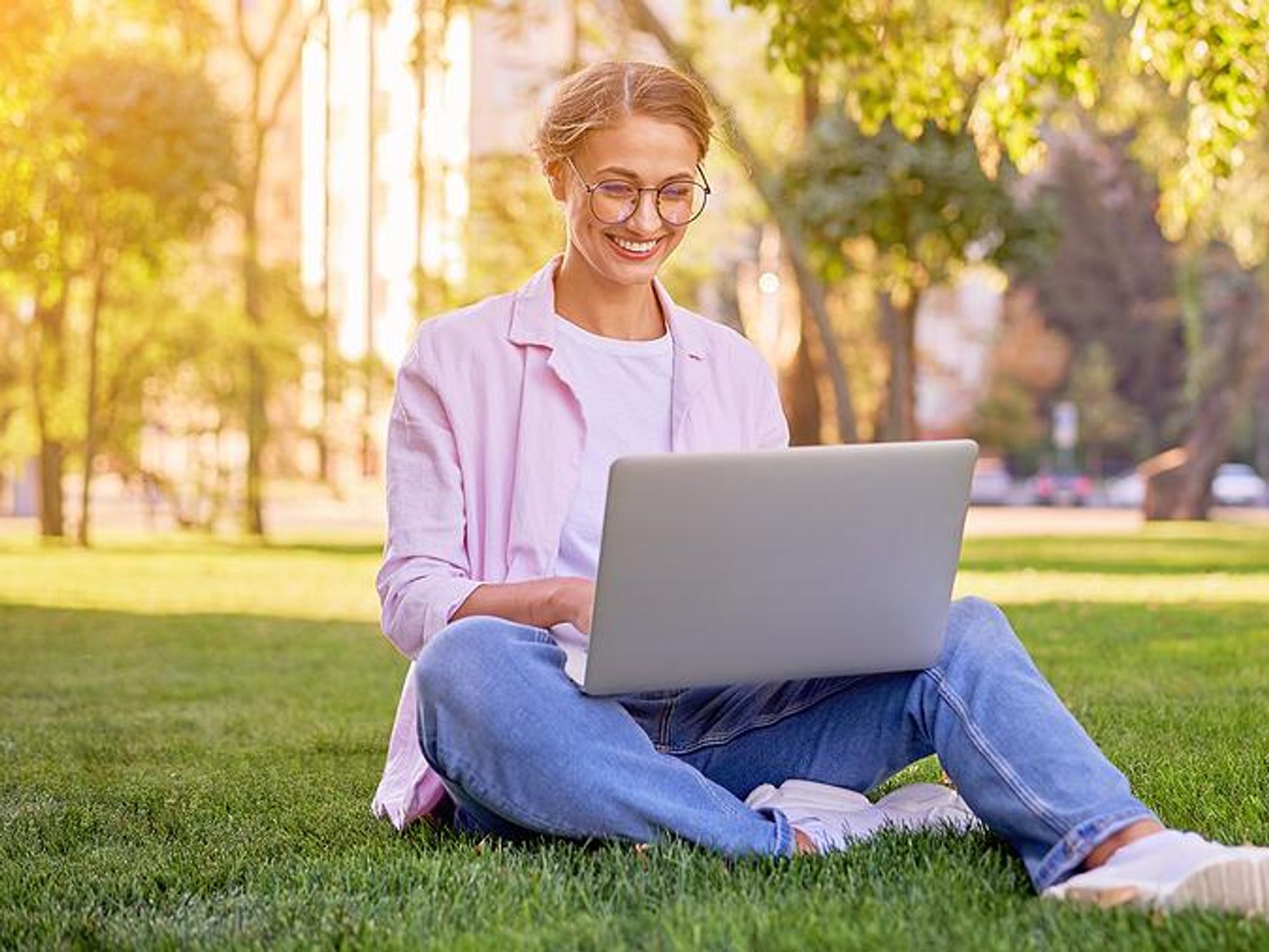 Woman sitting on grass types on her laptop