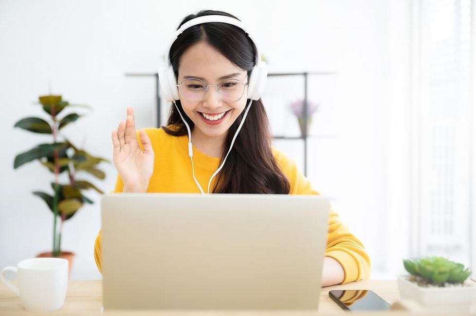 Woman smiles while talking to someone virtually on laptop