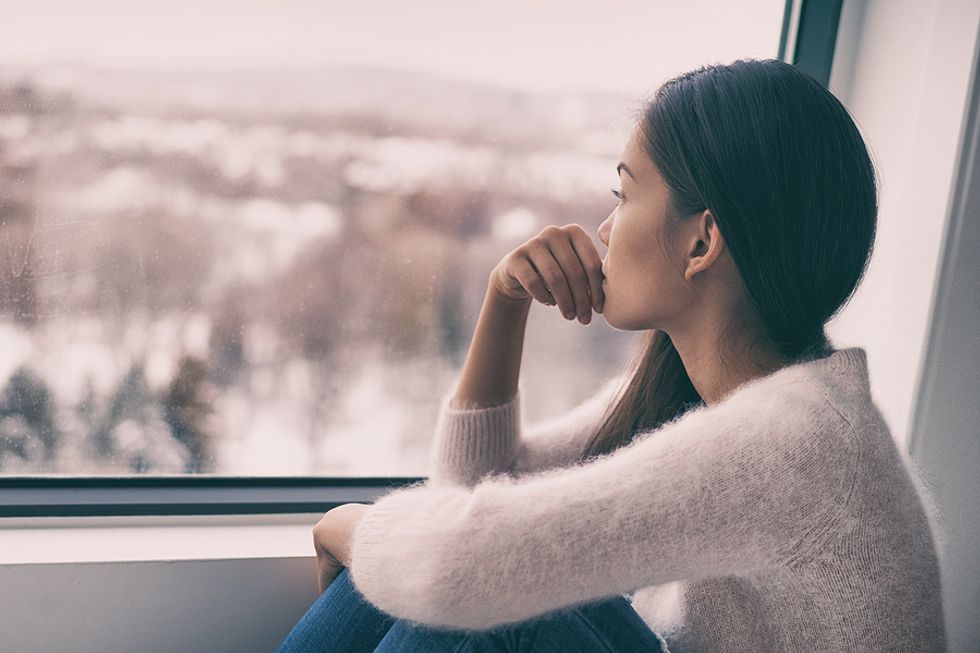Woman staring out a window doesn't feel confident in her job search