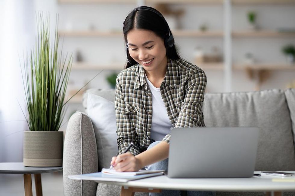Woman takes notes while working her work-from-anywhere job
