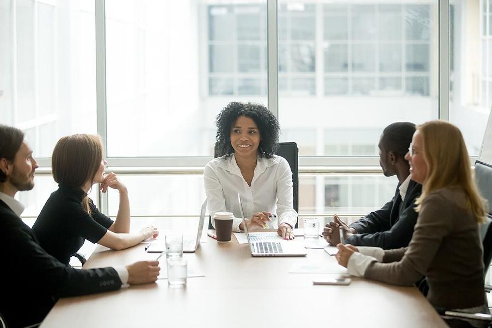 Mujer habla con ejecutivos y junta en reunión de negocios
