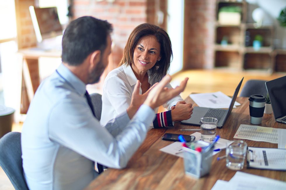 Woman talks to her coworker for help with building her personal brand on her resume