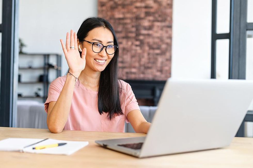 Woman waves to someone during a virtual job interview