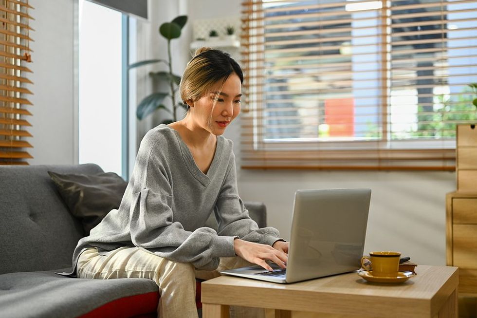 Woman working from home on laptop deals with remote work loneliness