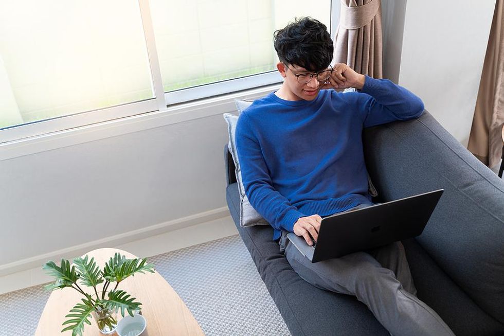 Young man on laptop edits his resume