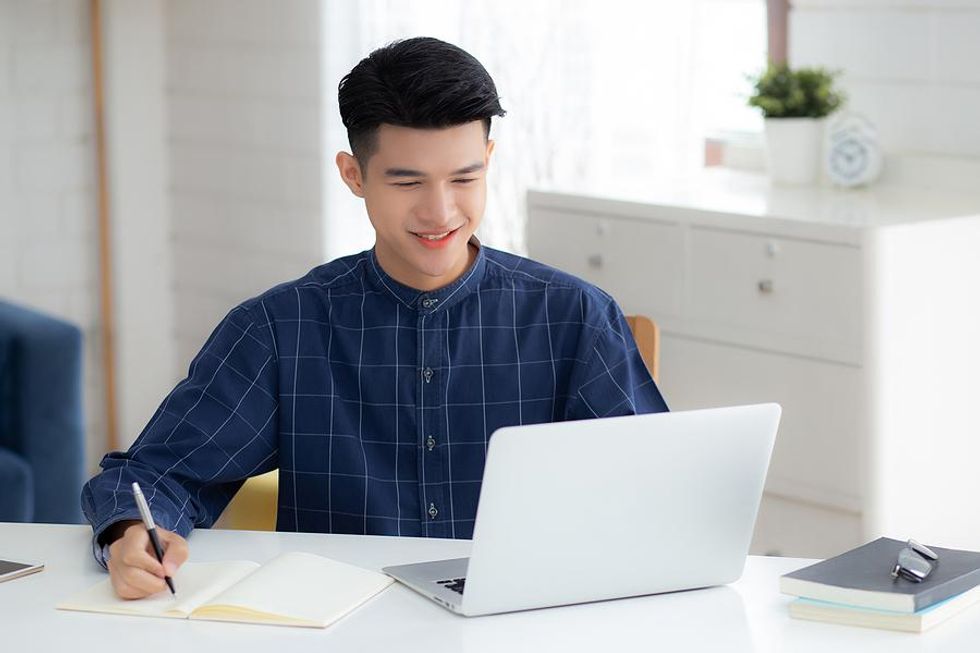 Young man on laptop outlines his personal brand and takes notes