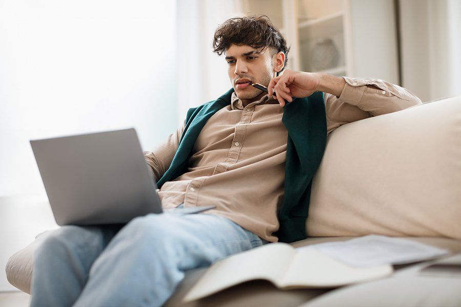 Young man on laptop thinks about his future and tries to choose a career path