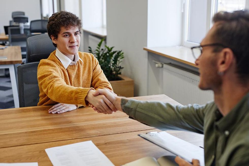 Young man mixtures hands with the employing manager before a job interview