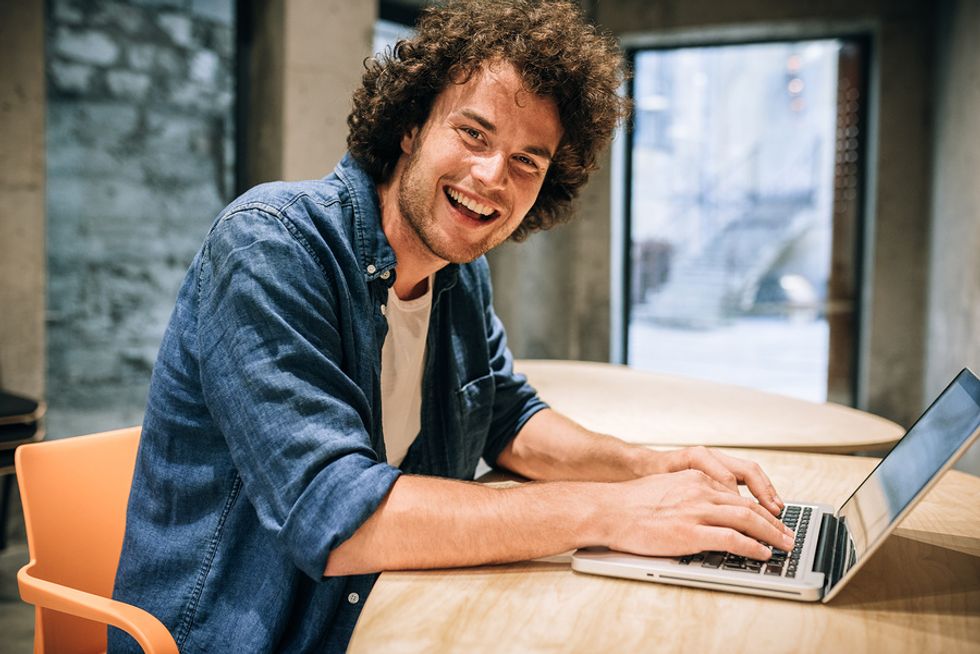 Young man smiling at his desk and happy to be at work.