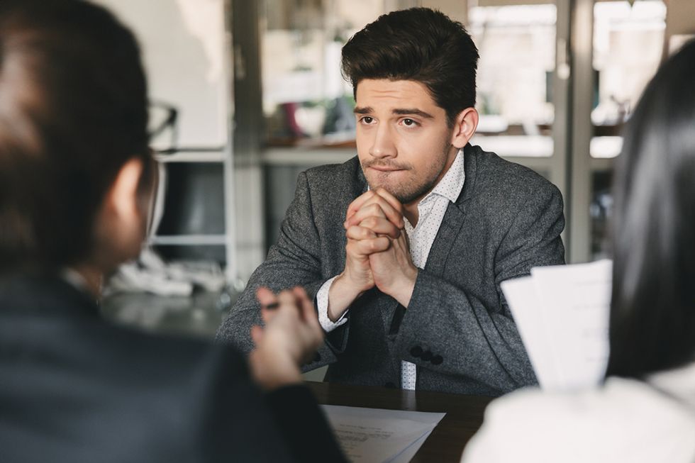 Young professional man debating whether or not he should turn down a job offer during a job interview.