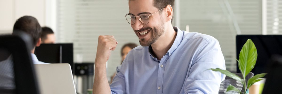 Young professional man looking excited at his desk because he's confident that he's found a job he's passionate about.