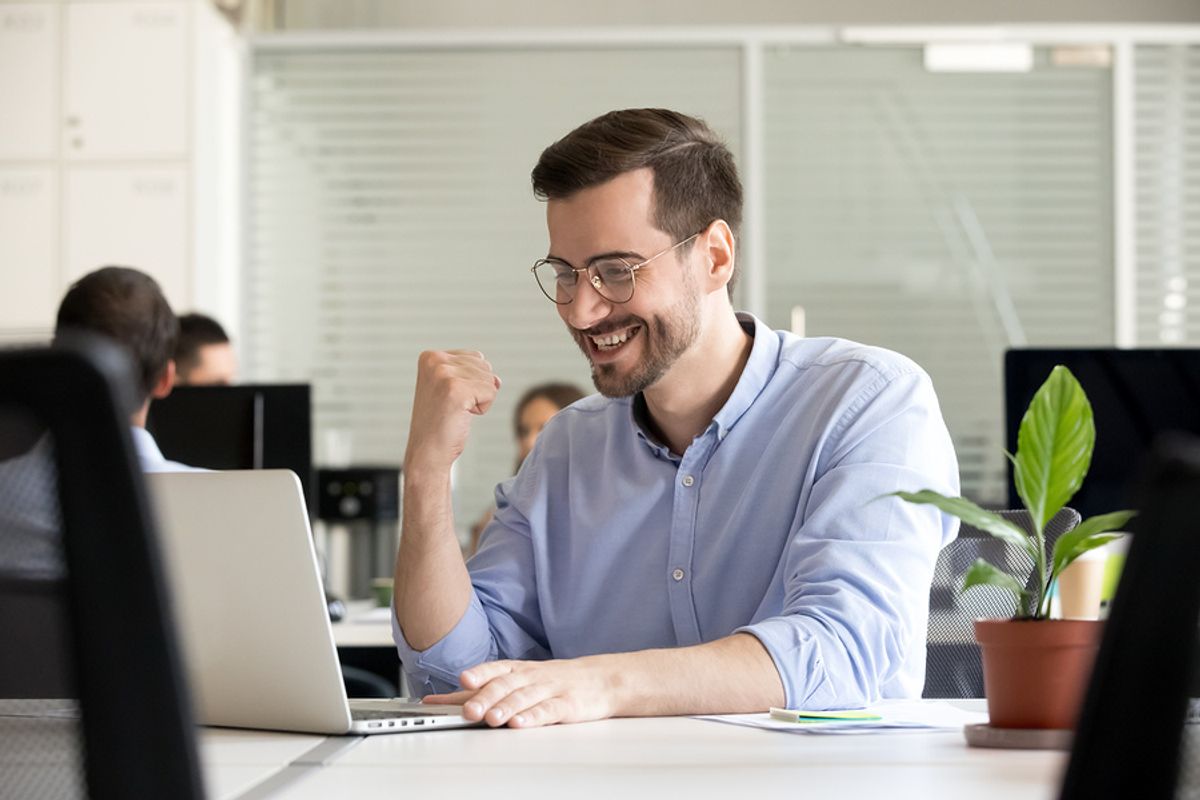Young professional man looking excited at his desk because he's confident that he's found a job he's passionate about.