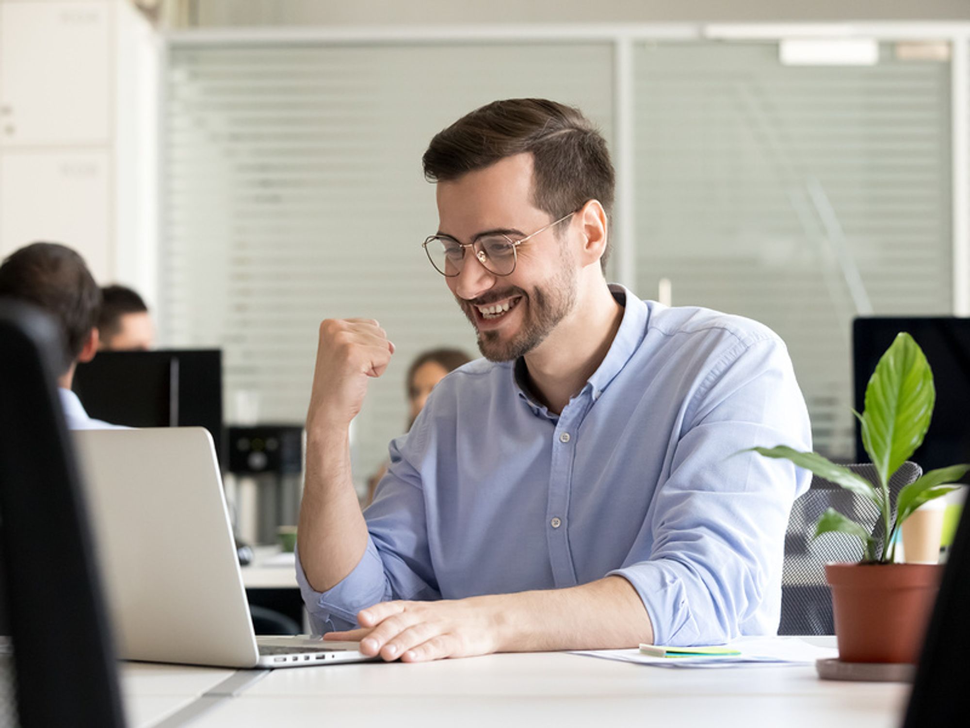 Young professional man looking excited at his desk because he's confident that he's found a job he's passionate about.