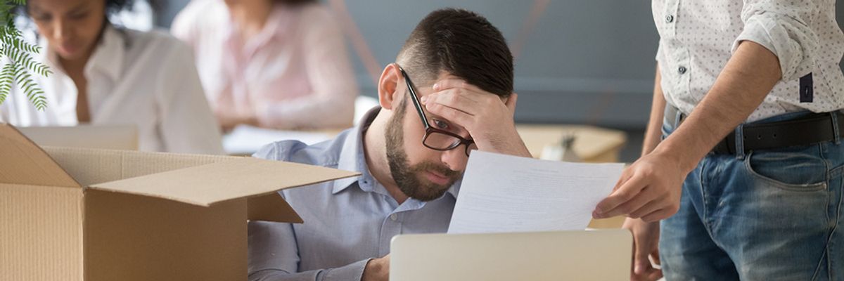 Young professional man looking sad at his desk after realizing he's being laid off