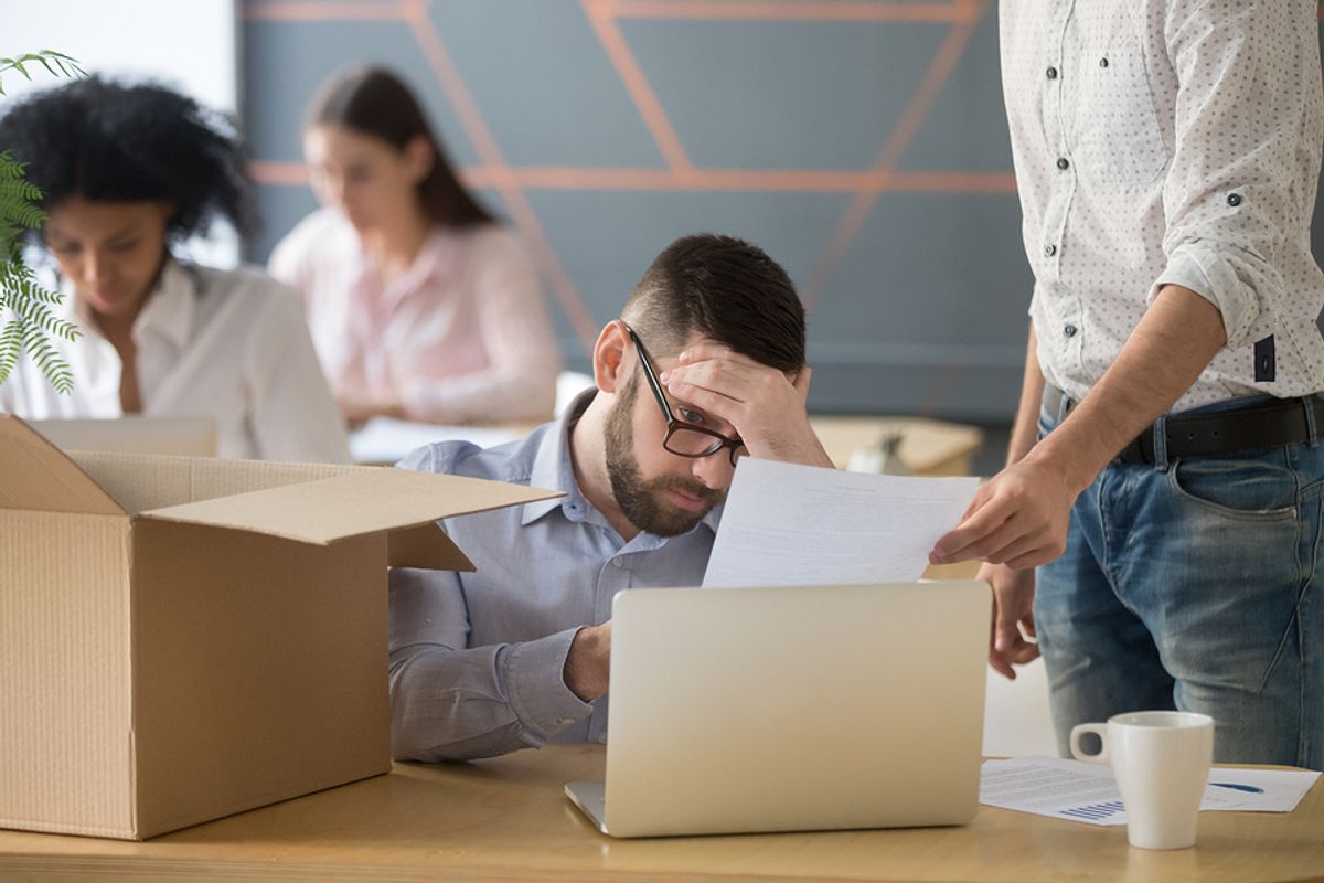 Young professional man looking sad at his desk after realizing he's being laid off