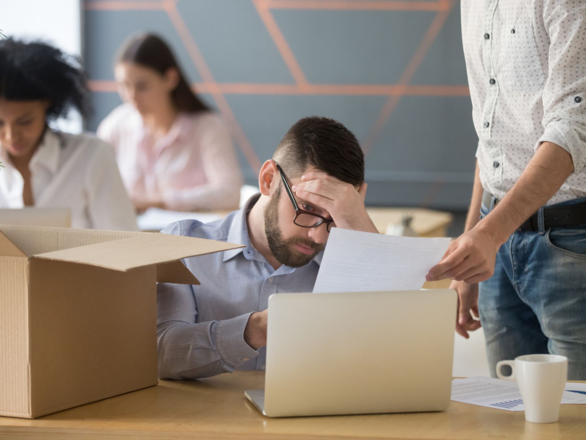 Young professional man looking sad at his desk after realizing he's being laid off