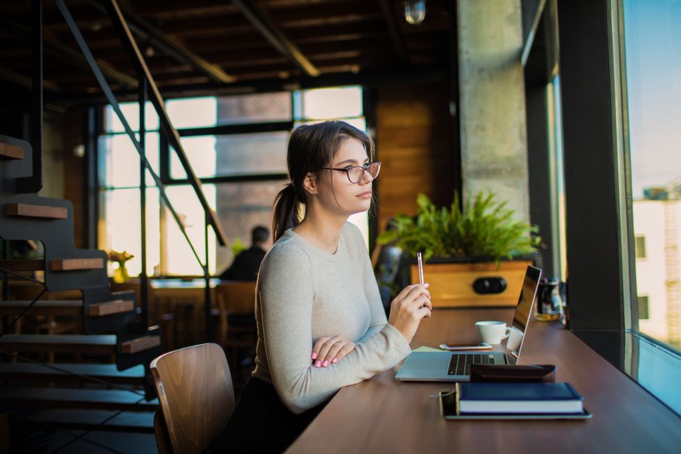 Young professional on laptop thinks about introducing two colleagues