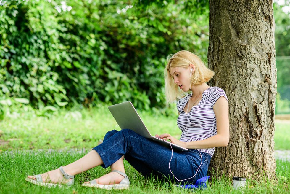 Young professional on laptop works on her job search while enjoying the summer weather
