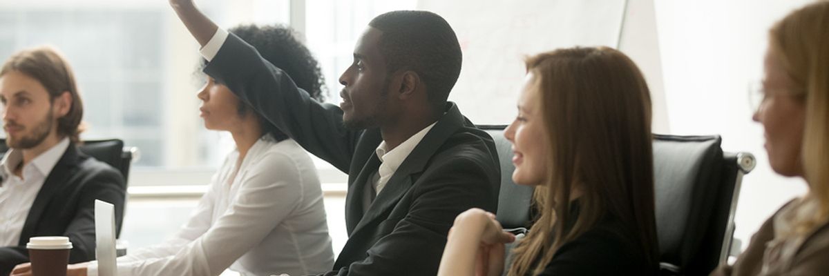 Young professional raises hand to ask a question about changes at the company.