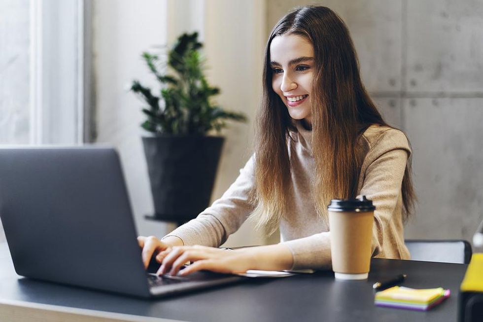Young professional woman on laptop works on her resume