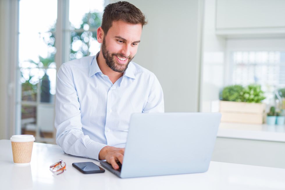 Young unemployed man establishing an online presence by writing a blog post while he's looking for work