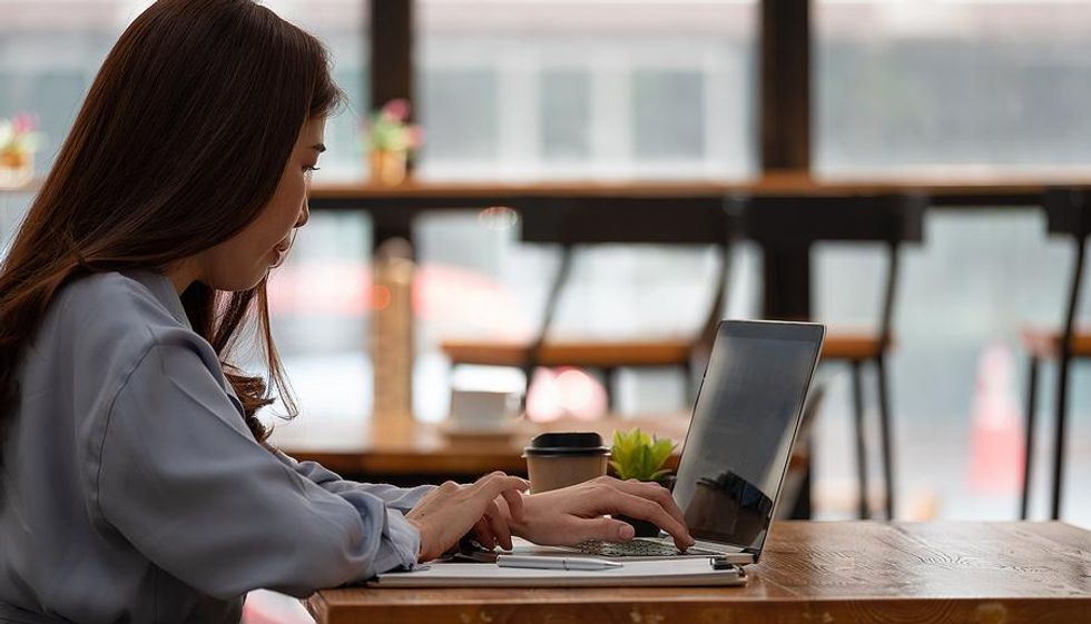 Young woman at a caf\u00e9 while working at her entry-level remote job