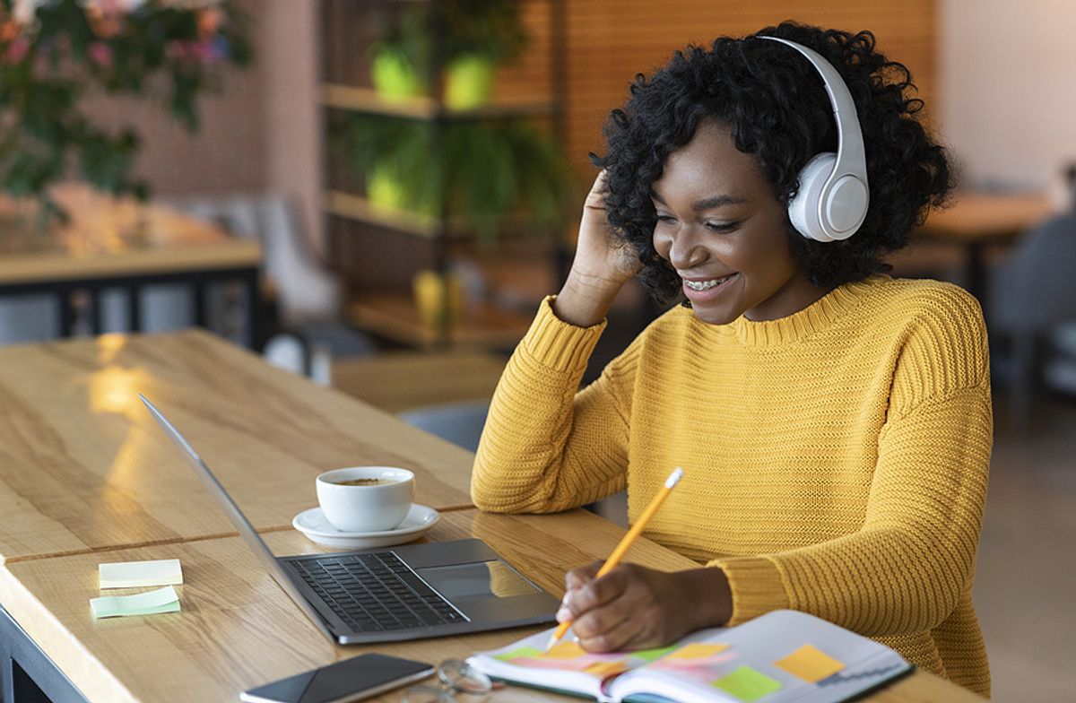 Young woman listens to podcast episodes while doing homework