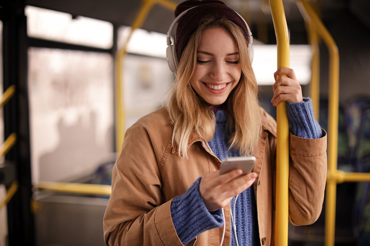 Young woman listens to podcast episodes while on the bus