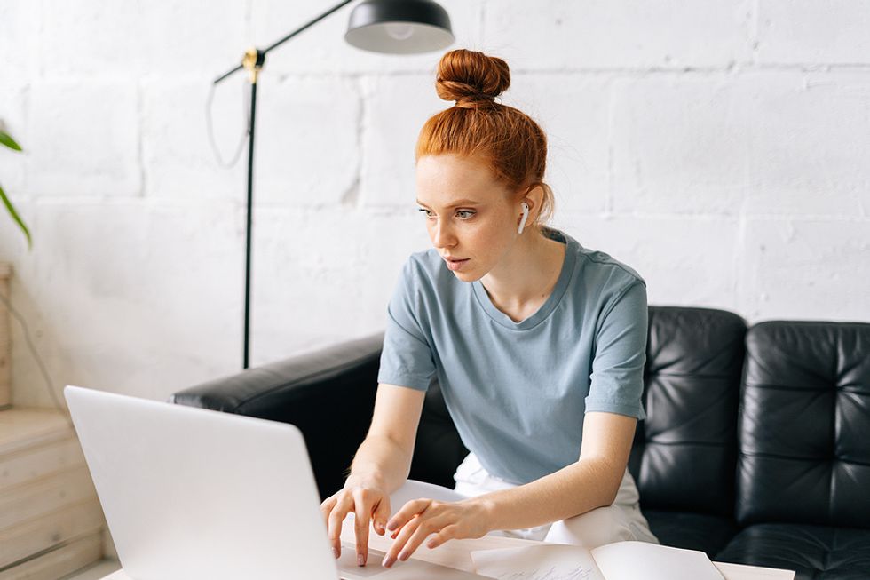 Young woman listens to podcast episodes while working