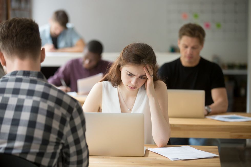 Young woman looking sad at her desk because she's not making friends at work as quickly as she'd like.