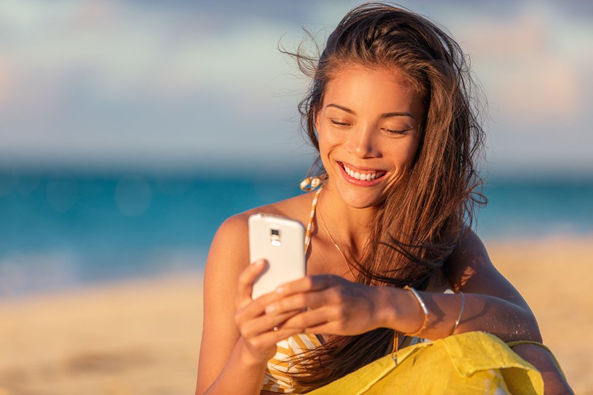 Young woman networks briefly on her phone while on summer vacation