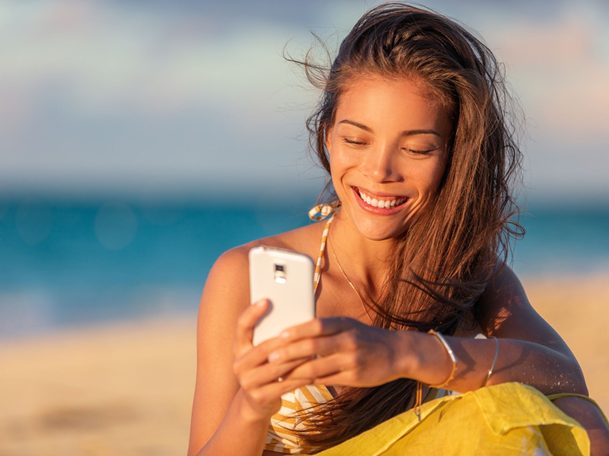 Young woman networks briefly on her phone while on summer vacation.