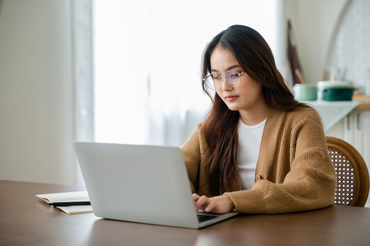 Young woman on laptop writes an email without using email phrases to avoid at work