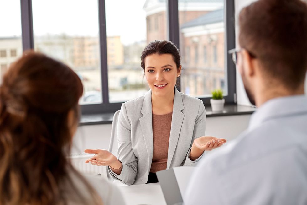 Young woman practicing her delivery with two co-workers before her next job interview.